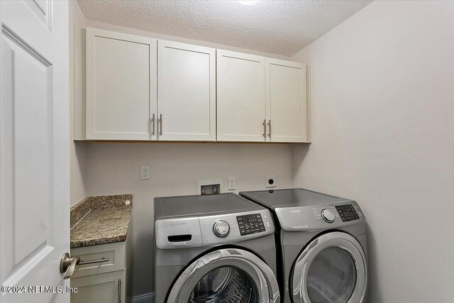 clothes washing area with cabinets, a textured ceiling, and separate washer and dryer