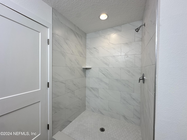 bathroom with a tile shower and a textured ceiling