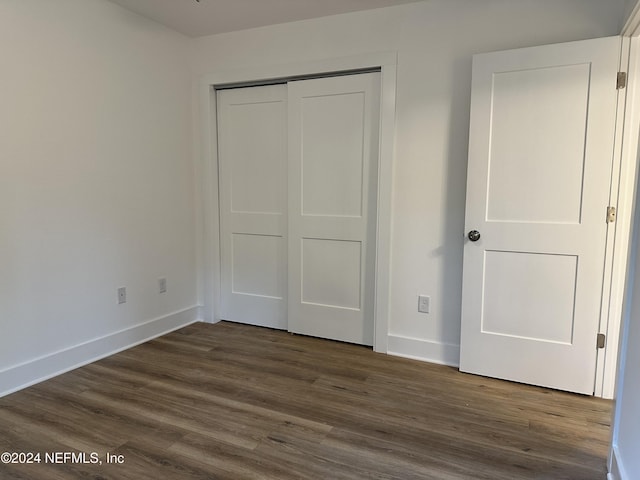 unfurnished bedroom featuring dark hardwood / wood-style floors and a closet