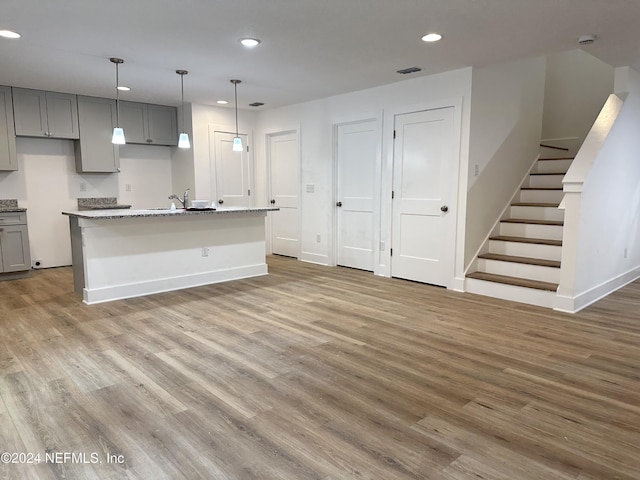 kitchen featuring gray cabinets, a center island with sink, and hardwood / wood-style flooring