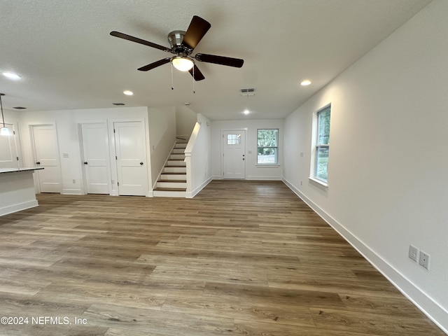 unfurnished living room featuring ceiling fan and wood-type flooring