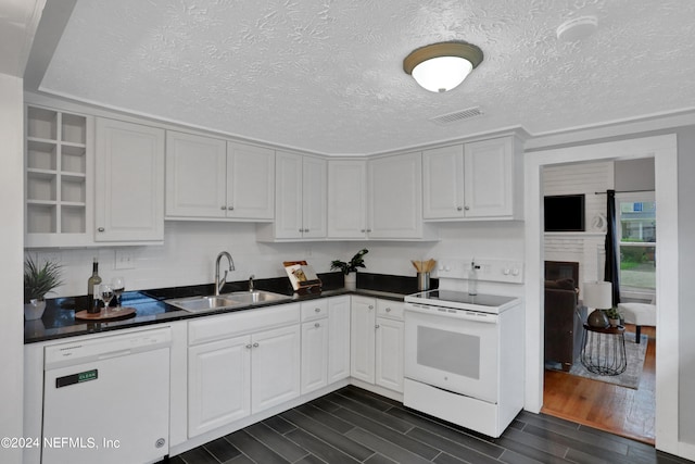 kitchen featuring sink, white appliances, a textured ceiling, white cabinetry, and dark hardwood / wood-style flooring