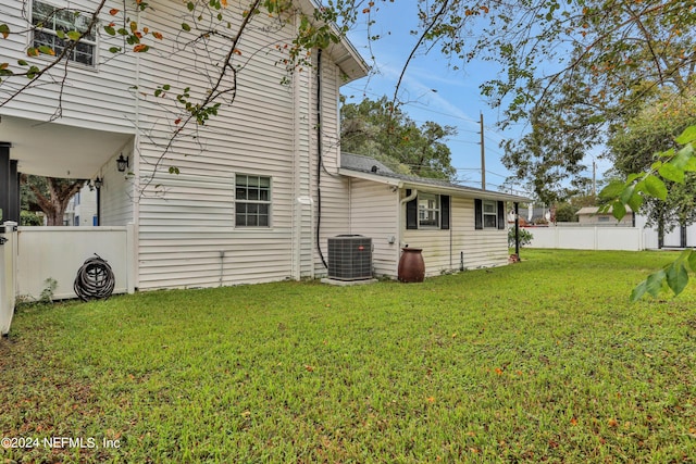 rear view of property featuring central AC unit and a yard