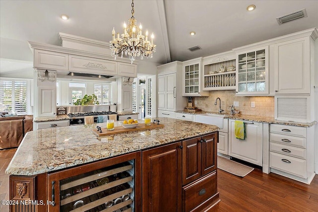 kitchen with hanging light fixtures, tasteful backsplash, beverage cooler, a center island, and dark hardwood / wood-style flooring