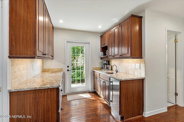 kitchen featuring light stone countertops, dark hardwood / wood-style flooring, sink, and tasteful backsplash