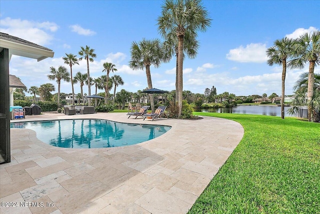 view of pool with a lawn, a patio, and a water view