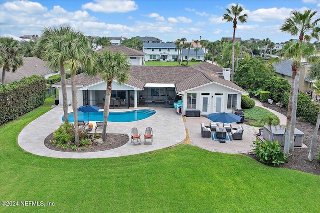 rear view of property featuring outdoor lounge area, a yard, and a patio