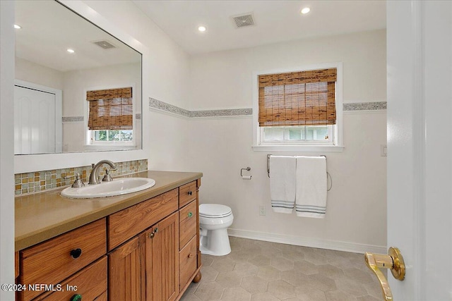 bathroom with tile patterned floors, plenty of natural light, vanity, and toilet