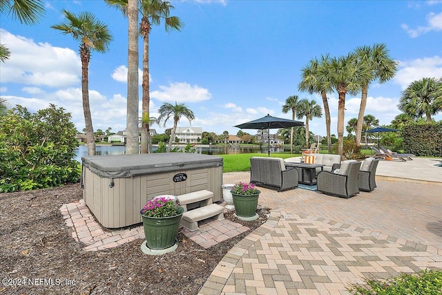 view of patio / terrace with a hot tub, a water view, and an outdoor hangout area