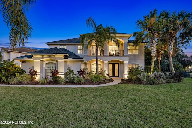 mediterranean / spanish home featuring a balcony, french doors, and a yard