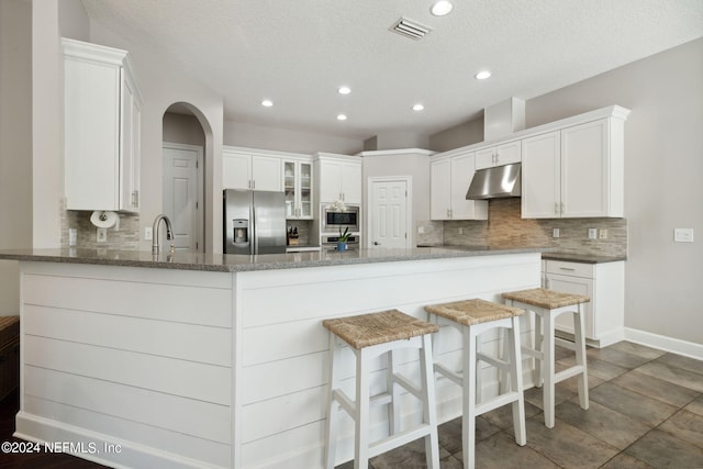 kitchen with kitchen peninsula, white cabinetry, stainless steel appliances, and a textured ceiling