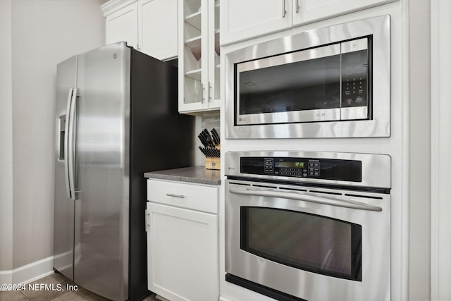 kitchen featuring white cabinetry, stainless steel appliances, and dark tile patterned flooring