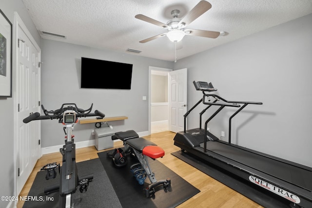 workout area with light hardwood / wood-style floors, a textured ceiling, and ceiling fan