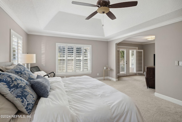 carpeted bedroom featuring ceiling fan, a textured ceiling, a tray ceiling, ornamental molding, and french doors