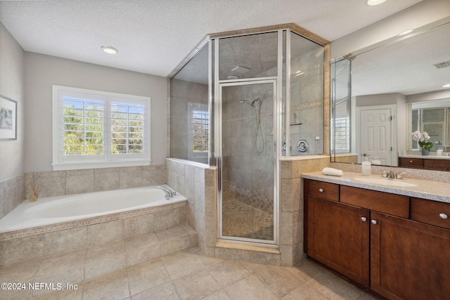 bathroom with vanity, a textured ceiling, independent shower and bath, and tile patterned floors