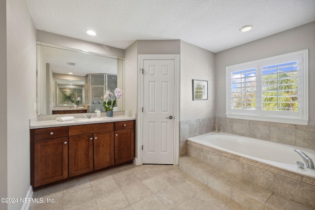 bathroom with vanity, tiled bath, and a textured ceiling