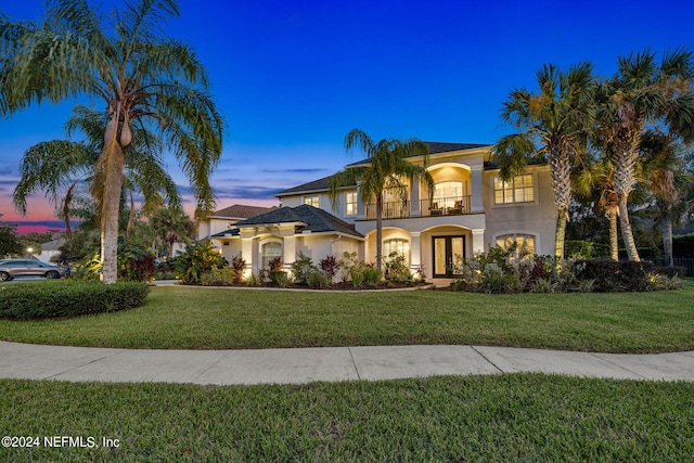 mediterranean / spanish-style home with a lawn and a balcony