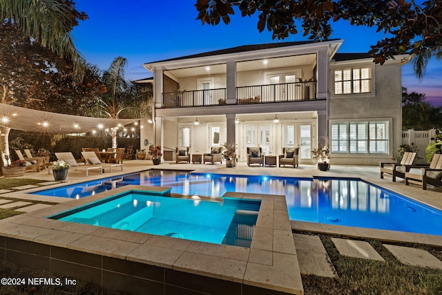 exterior space with a balcony, a swimming pool with hot tub, an outdoor hangout area, and a patio area