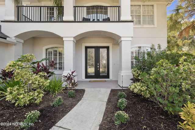 view of exterior entry featuring a balcony and french doors