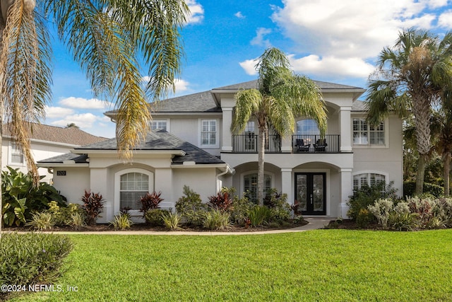 view of front of property featuring french doors, a balcony, and a front lawn