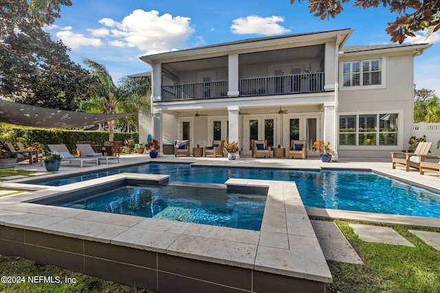 rear view of property with a balcony, a swimming pool with hot tub, an outdoor living space, and a patio