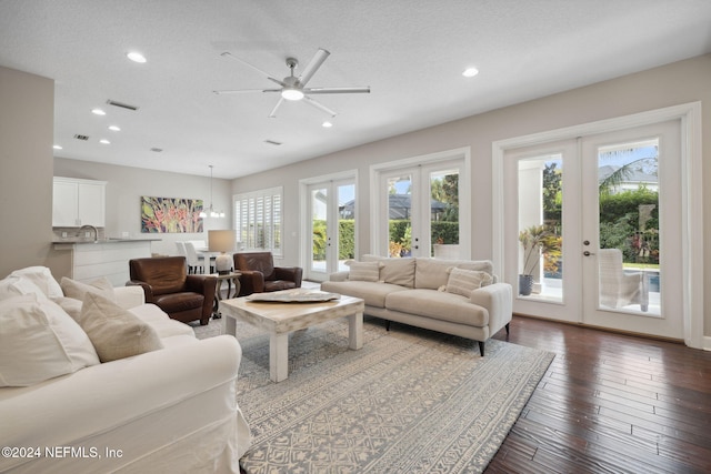 living room with french doors, a textured ceiling, dark wood-type flooring, and ceiling fan