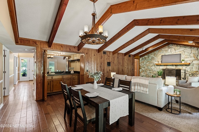 dining room featuring an inviting chandelier, wooden walls, vaulted ceiling with beams, and dark hardwood / wood-style flooring