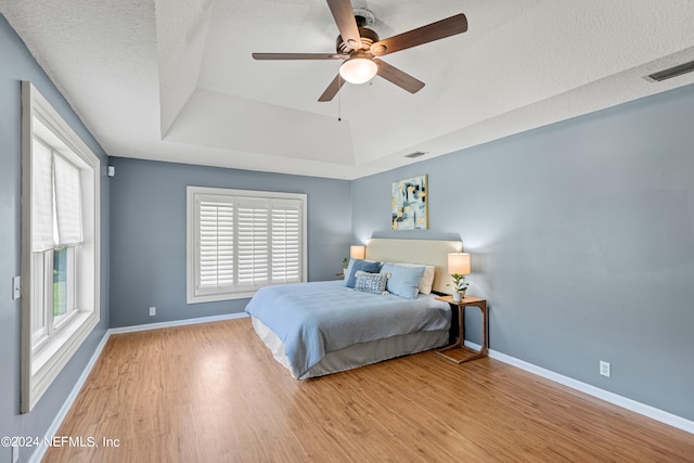 bedroom with light hardwood / wood-style floors, multiple windows, ceiling fan, and a textured ceiling