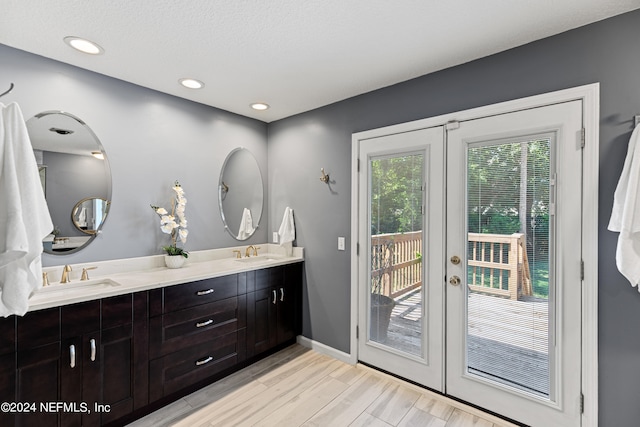 bathroom with french doors, vanity, a textured ceiling, and hardwood / wood-style floors