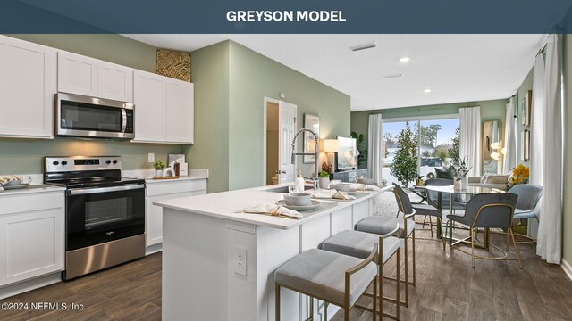 kitchen featuring an island with sink, stainless steel appliances, and white cabinets