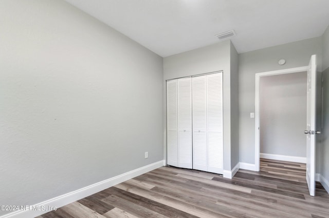 unfurnished bedroom with wood-type flooring and a closet