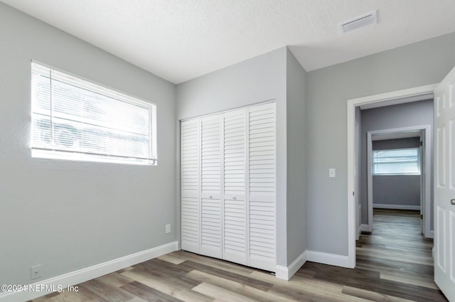 unfurnished bedroom featuring a textured ceiling, a closet, and light hardwood / wood-style floors