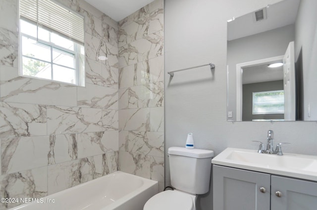 full bathroom featuring vanity, tiled shower / bath combo, and toilet