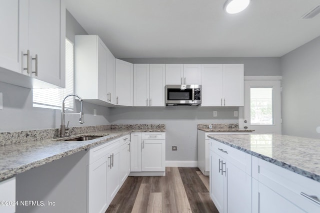 kitchen featuring dark hardwood / wood-style flooring, white cabinetry, light stone countertops, and sink