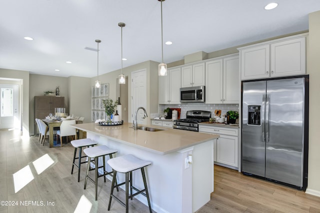 kitchen with an island with sink, stainless steel appliances, white cabinets, and sink