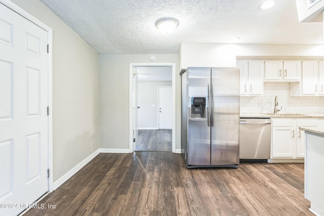 kitchen featuring appliances with stainless steel finishes, dark hardwood / wood-style floors, sink, and white cabinetry