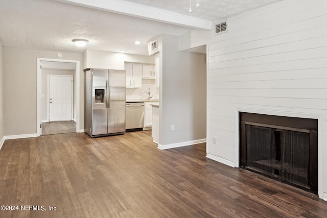 unfurnished living room with a textured ceiling, hardwood / wood-style floors, and sink