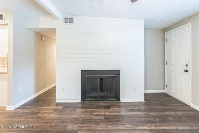 unfurnished living room featuring a textured ceiling and dark hardwood / wood-style floors