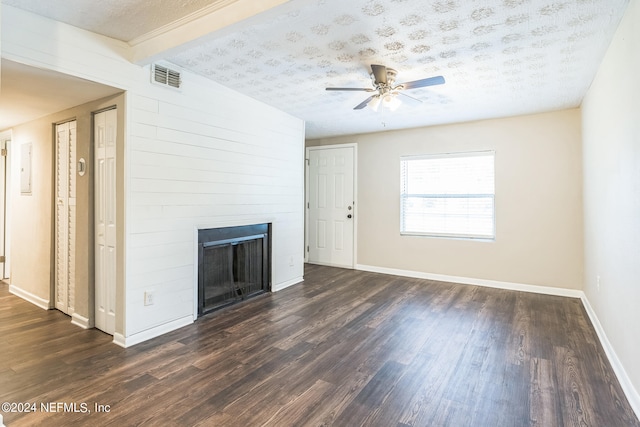 unfurnished living room featuring ceiling fan, beam ceiling, a textured ceiling, dark hardwood / wood-style floors, and a fireplace