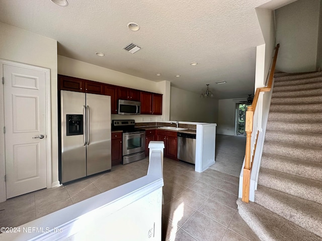 kitchen with light tile patterned floors, stainless steel appliances, a textured ceiling, sink, and a chandelier