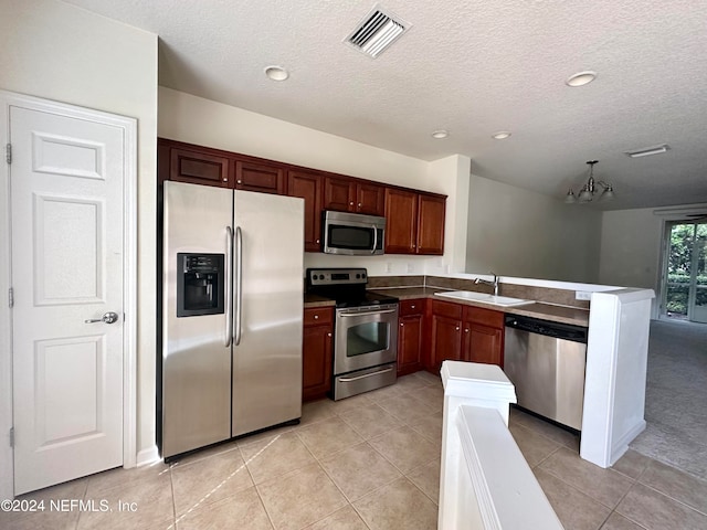 kitchen featuring stainless steel appliances, kitchen peninsula, light tile patterned flooring, and sink