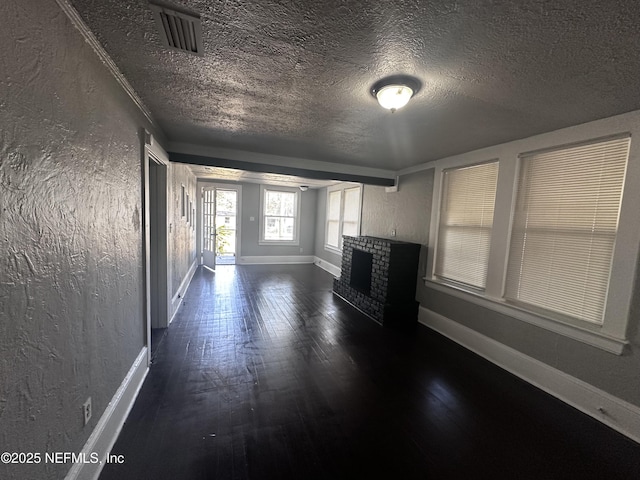 unfurnished living room featuring a fireplace, visible vents, and a textured wall