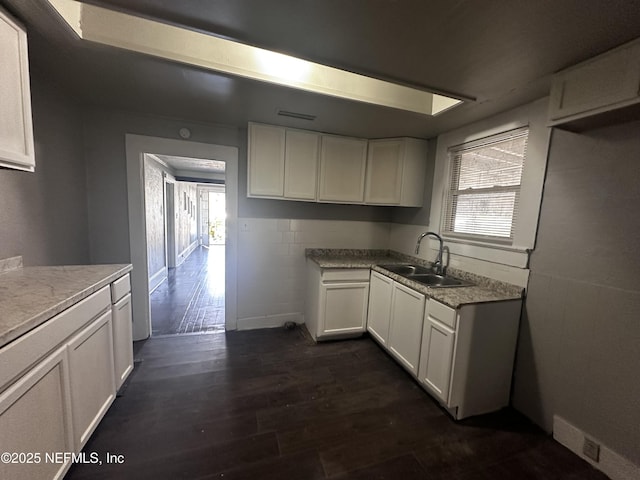 kitchen featuring dark wood-style flooring, white cabinets, a sink, and visible vents