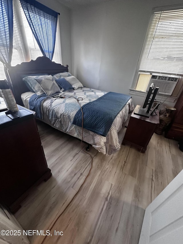 bedroom with cooling unit and wood finished floors