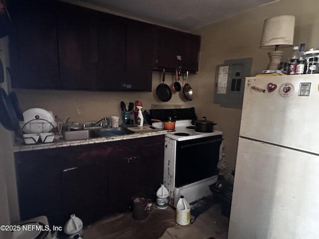 kitchen with white appliances, a sink, light countertops, dark cabinetry, and electric panel