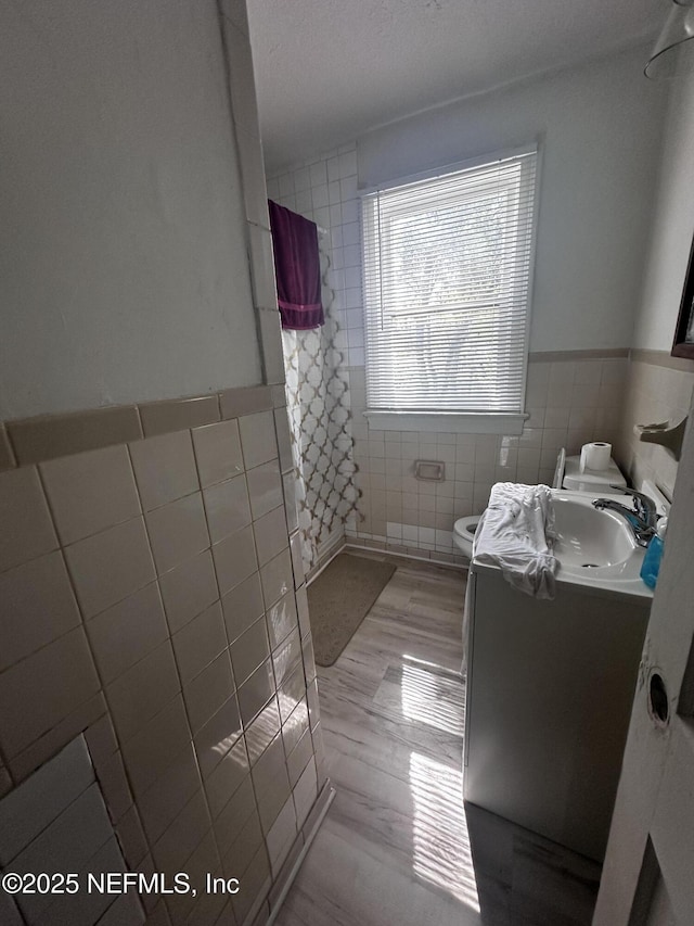 full bath featuring toilet, vanity, tile walls, and a shower with curtain