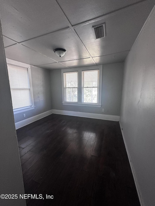 spare room featuring baseboards, visible vents, and dark wood-type flooring