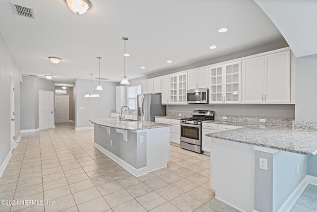 kitchen featuring sink, hanging light fixtures, a kitchen breakfast bar, a center island with sink, and appliances with stainless steel finishes