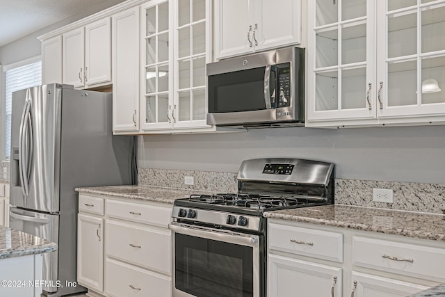 kitchen featuring appliances with stainless steel finishes, light stone countertops, and white cabinets