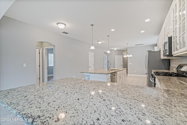 kitchen featuring light stone counters, pendant lighting, a kitchen island with sink, white cabinetry, and stainless steel appliances